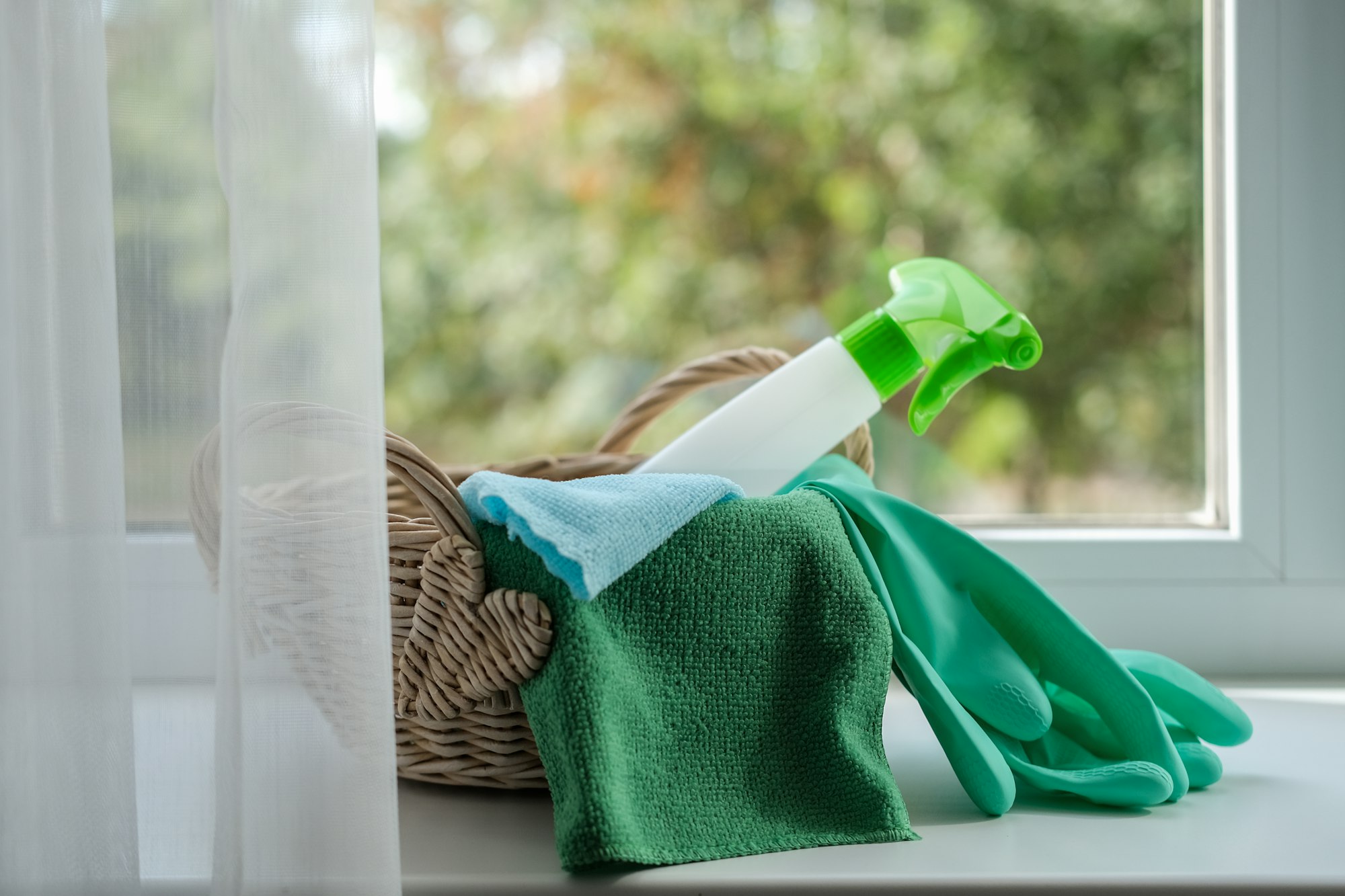 Cleaning agent, wipes and rubber gloves in a basket on the windowsill. General cleaning concept