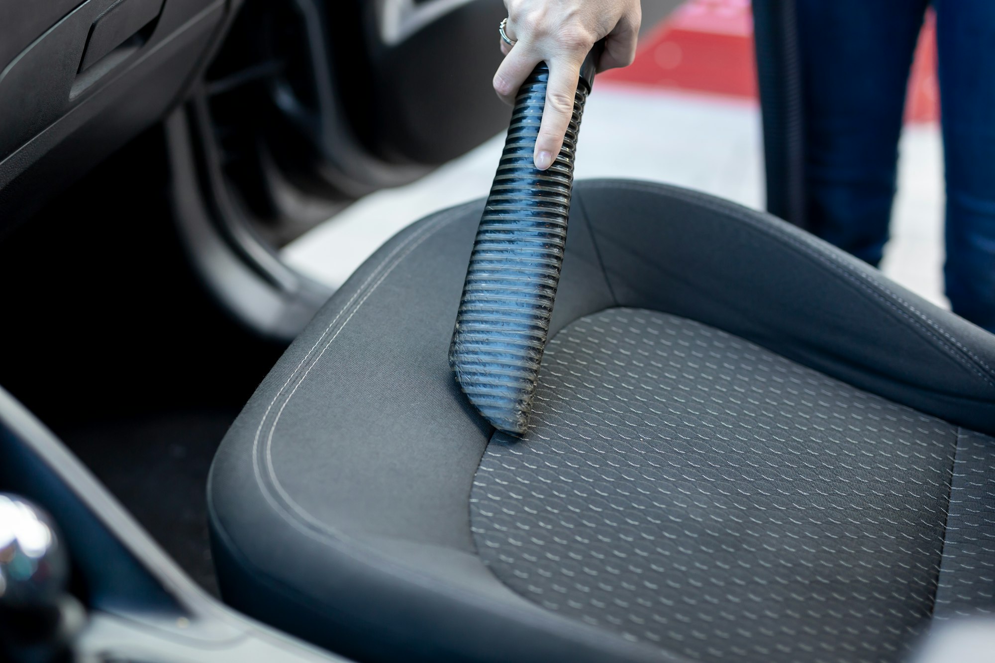 Woman vacuum cleaning car interior